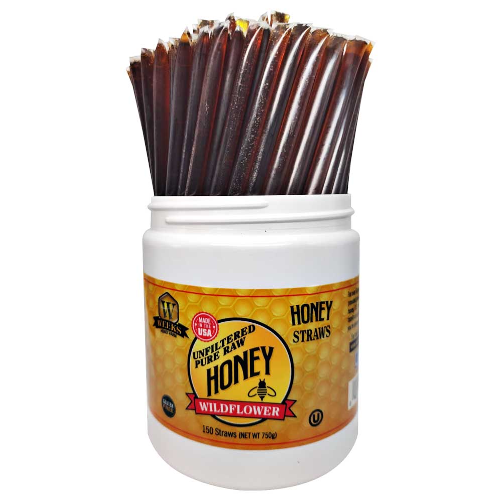 A white plastic container from Weeks Honey Farm labeled Raw Honey Straws | Orange Blossom, Wildflower, Raspberry Honey holds many clear straws filled with dark honey. The label features a honeycomb design and all-natural honey details.