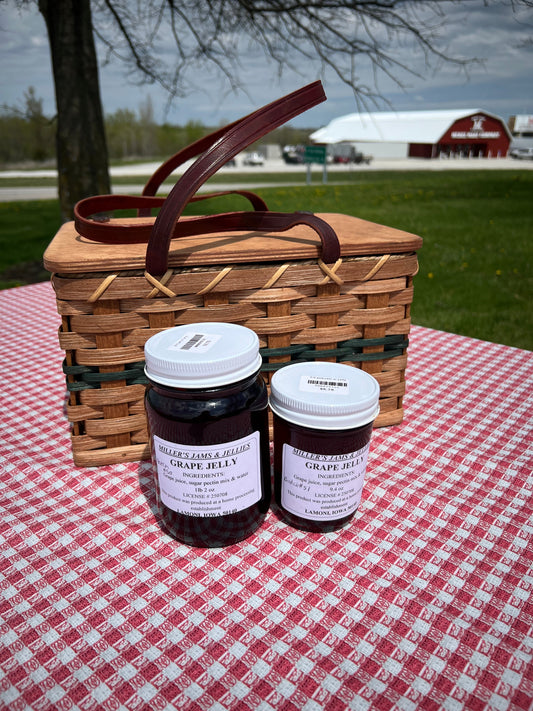 Glass jar of Amish Miller’s Grape Jelly by Amish Country Store with a label, showcasing the rich purple color of the jam.