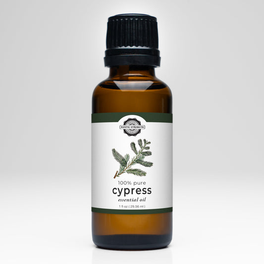 A brown glass bottle with a black cap, labeled Rustic Strength Cypress Essential Oil and featuring a cypress branch illustration, is 100% pure and comes in a 1 fl oz (29.56 ml) size—ideal for aromatherapy.