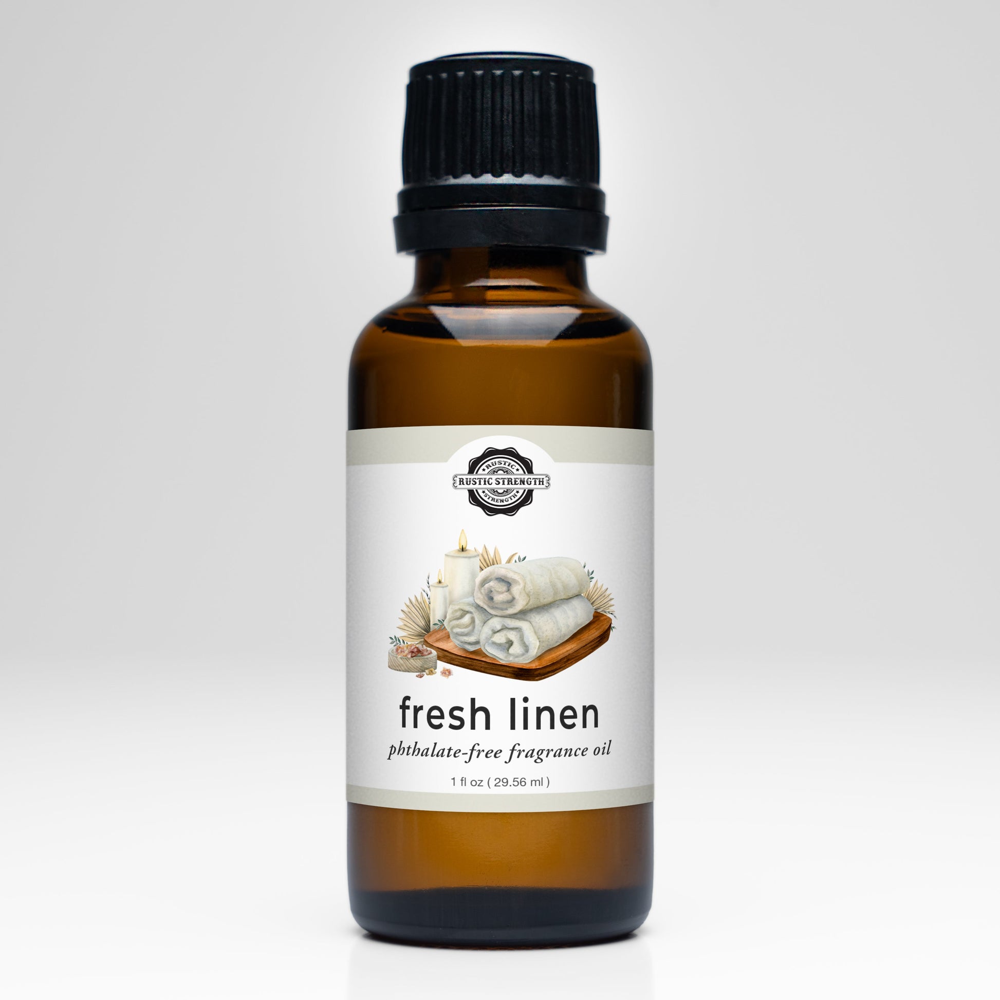 A brown glass bottle of Rustic Strength Fresh Linen Phthalate-Free Fragrance Oil features an illustration of rolled towels, candles, and flowers on the label. It stands on a white surface with a light gray background.