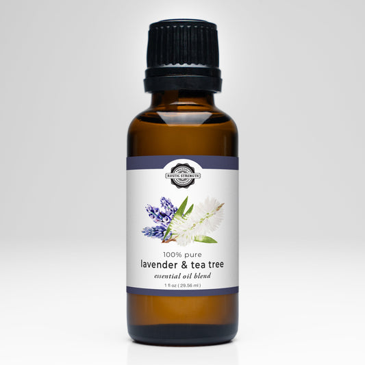A brown glass bottle with a black cap contains Rustic Strength’s Lavender & Tea Tree Essential Oil Blend. The white label features lavender and tea tree illustrations, highlighting its 100% pure formula—ideal for aromatherapy.