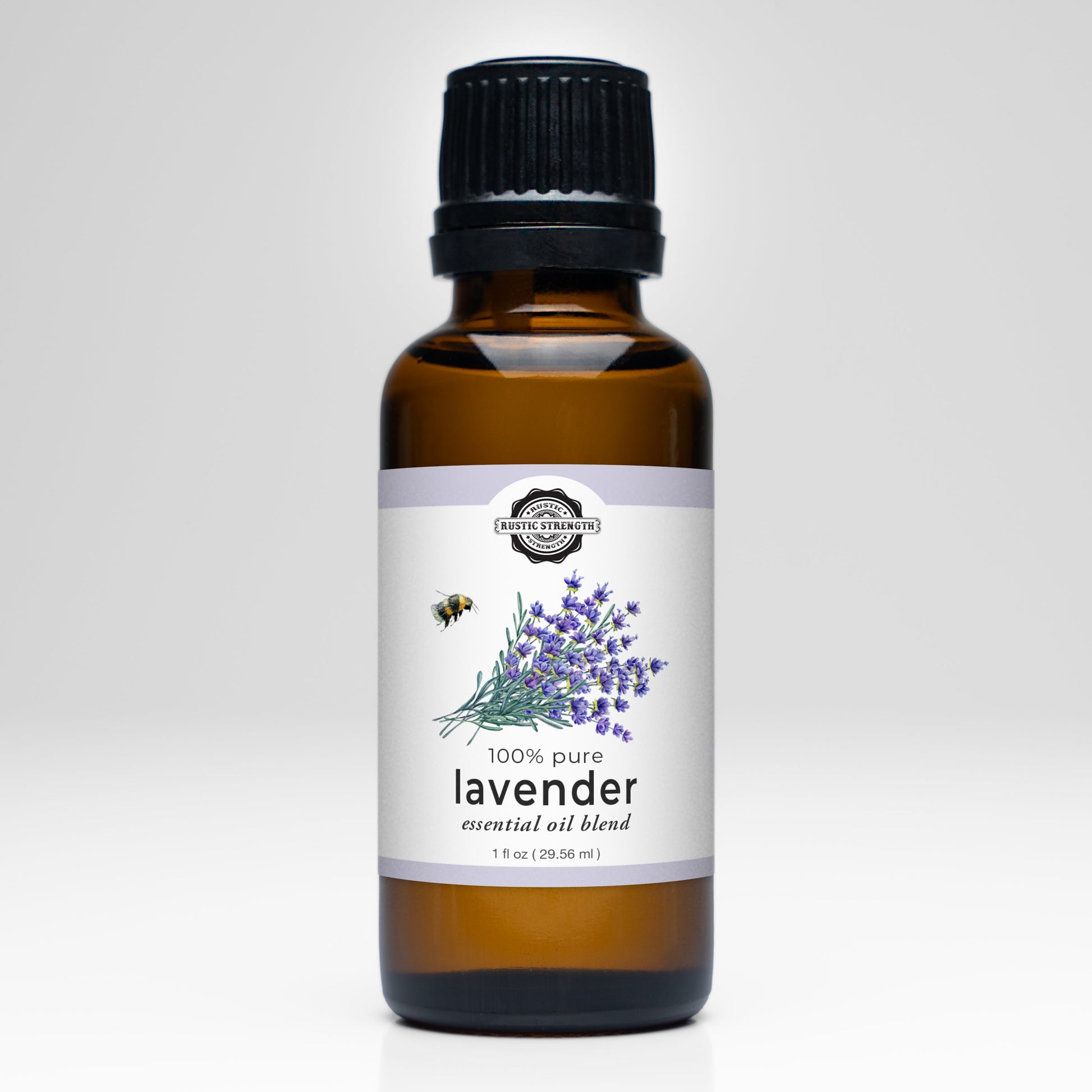 A 1 fl oz (29.55 mL) brown glass bottle of Rustic Strength Lavender Essential Oil features a black cap, a white label with lavender flowers and bee art, and is ideal for aromatherapy with its 100% pure premium blend.