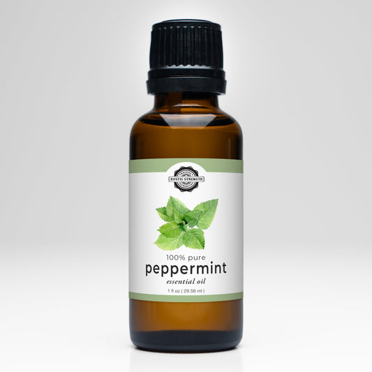 A brown glass bottle with a black cap labeled Rustic Strength Peppermint Essential Oil. The 1 fl oz (29.56 ml) label shows peppermint leaves and states its 100% pure. Ideal for aromatherapy, set against a plain white background.