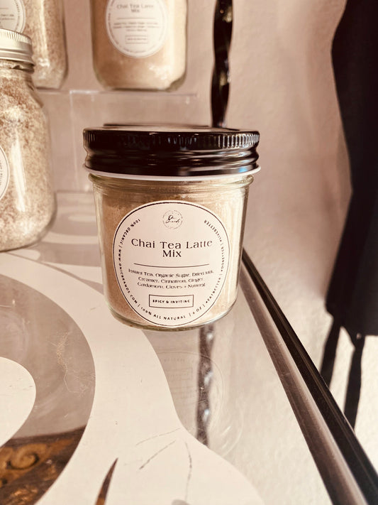 Creamy chai tea latte in a clear glass cup with cinnamon and tea leaves, served hot with a frothy top.
