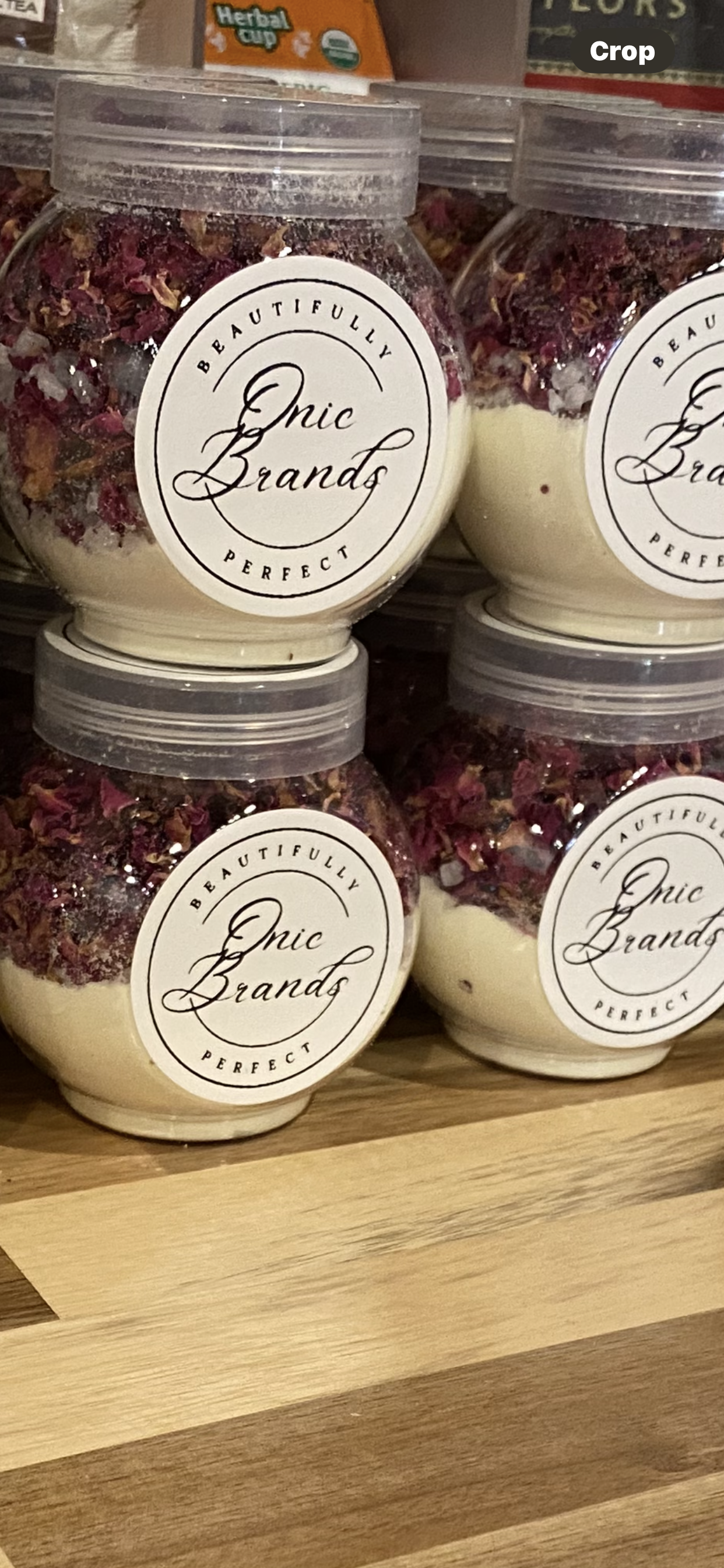 Onic Brands Cleopatra Bath Soak in a clear jar with a label, featuring pink and purple bath salts and floral accents.