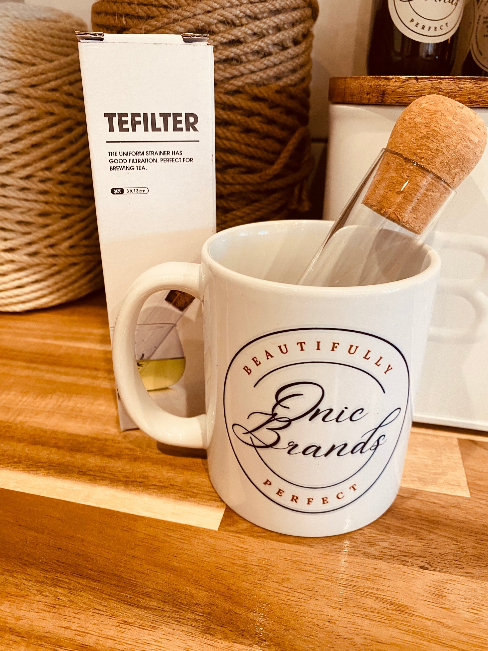 Tea test tube labeled TEFILTER by Onic Brands LLC, filled with tea leaves or sample, with a clear glass test tube and lid.