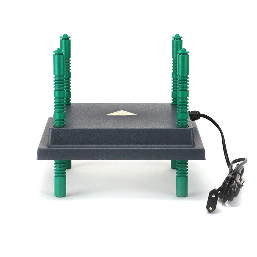 The image shows a My Pet Chicken Farmight Chick Brooder Heater Plate (black, rectangular) with adjustable height and four green legs pointing up, a power cord on the right, and a triangular label on top; the device is upside down.