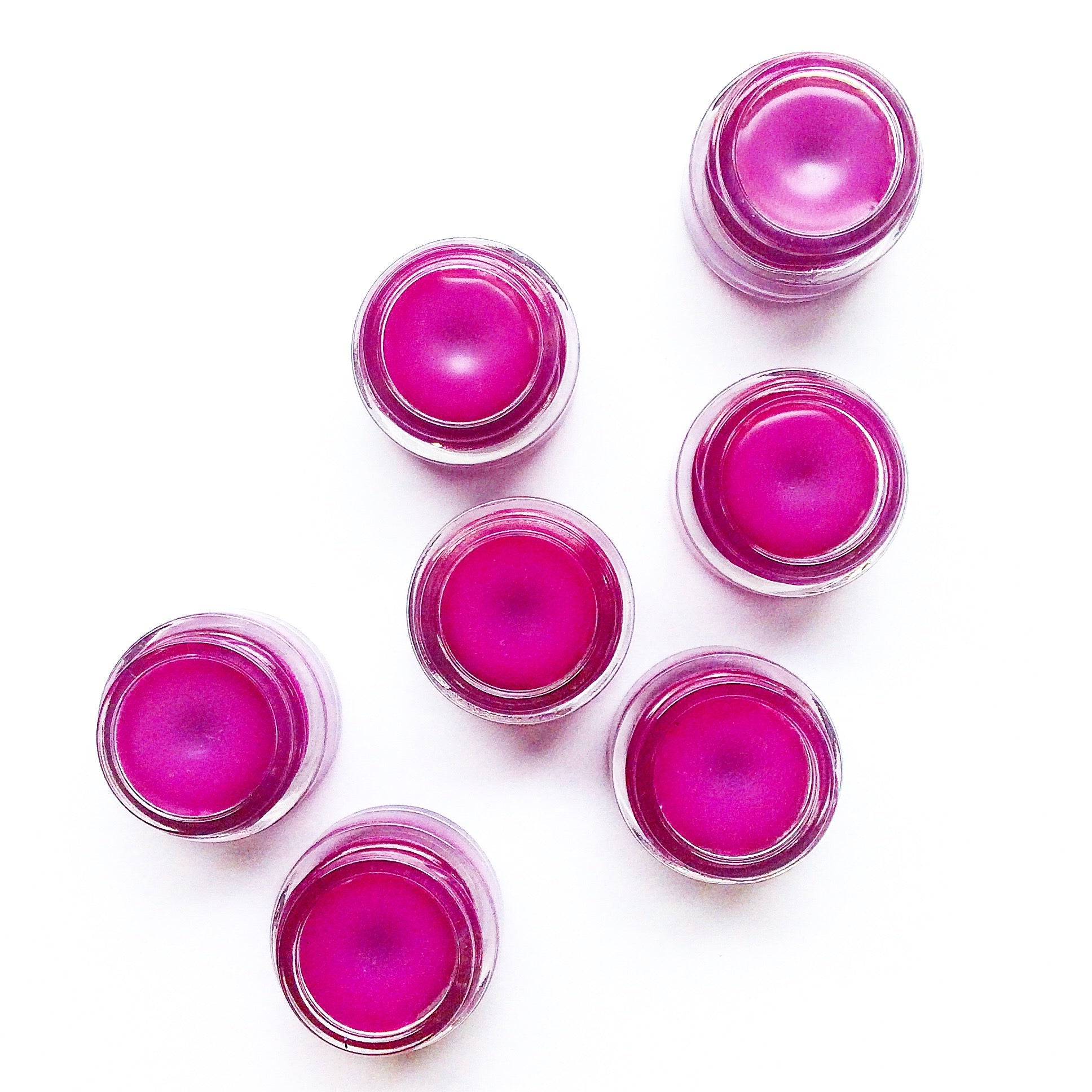 Plant Makeup dragon fruit lip gloss tube with vibrant pink packaging and clear label, close-up shot showing the product container.