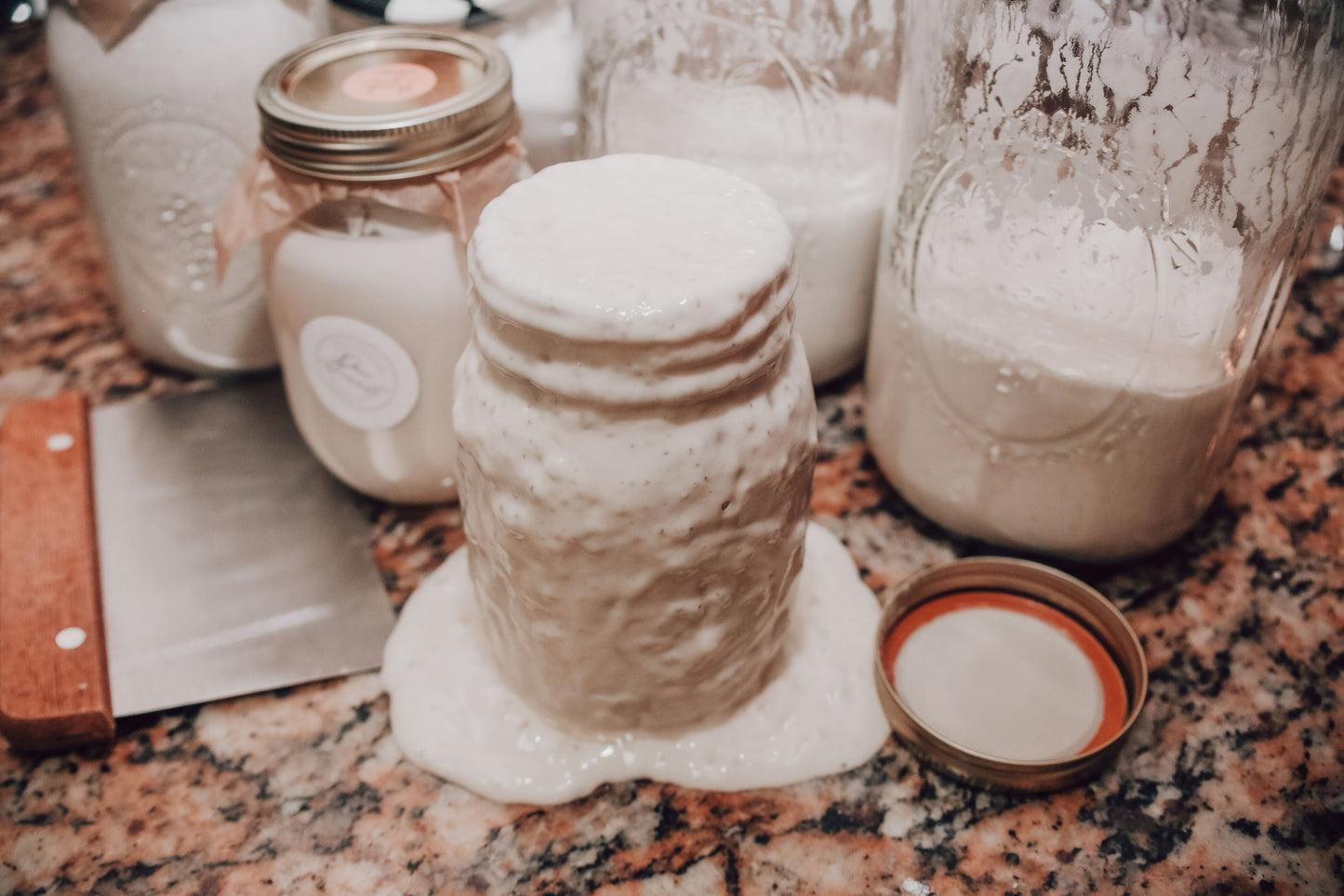 Onic Brands LLC sourdough starter jar with a clear label and a wooden spoon on a rustic wooden surface.