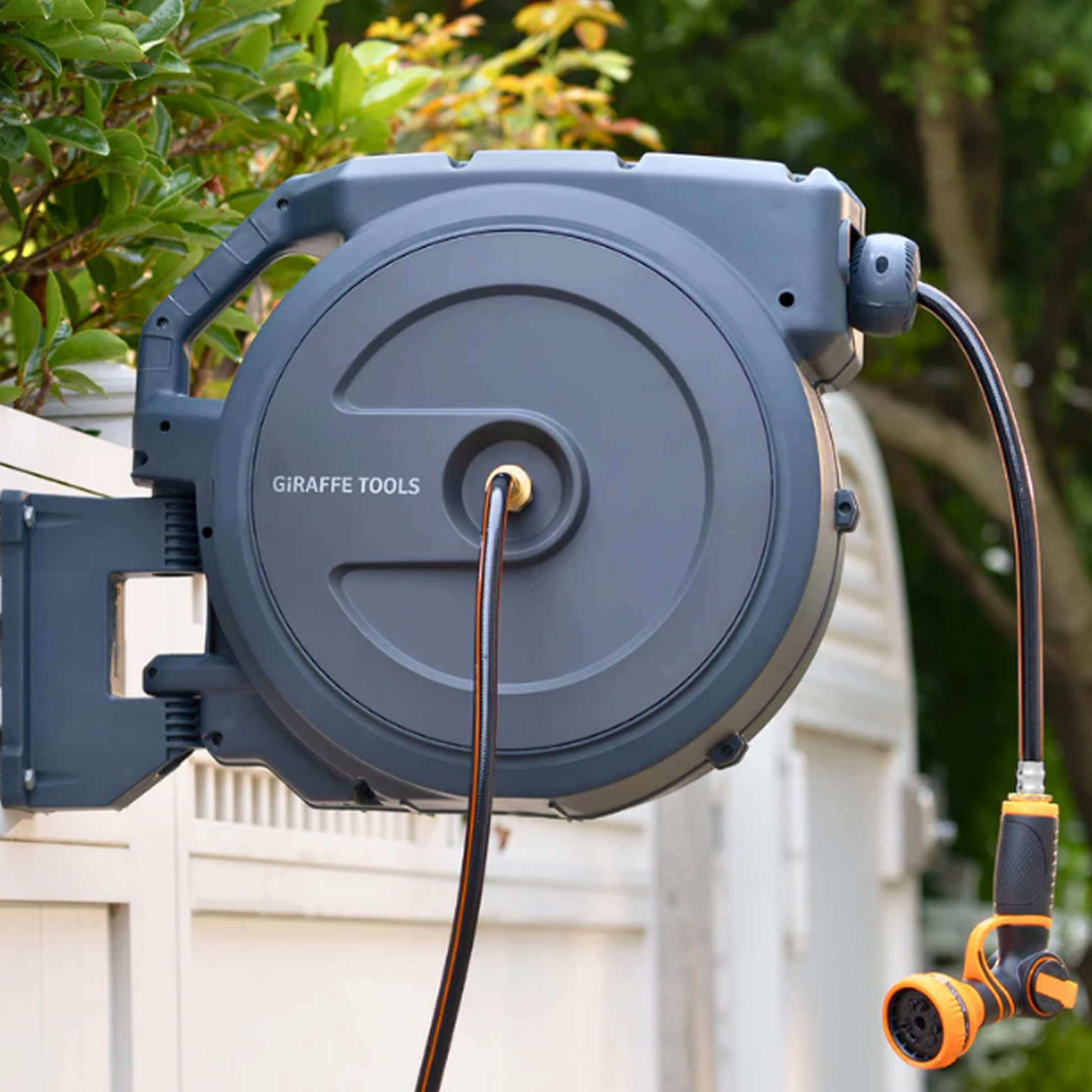 Giraffe Tools US retractable garden hose reel, 62 to 155 feet, with black and silver design, mounted in a garden setting