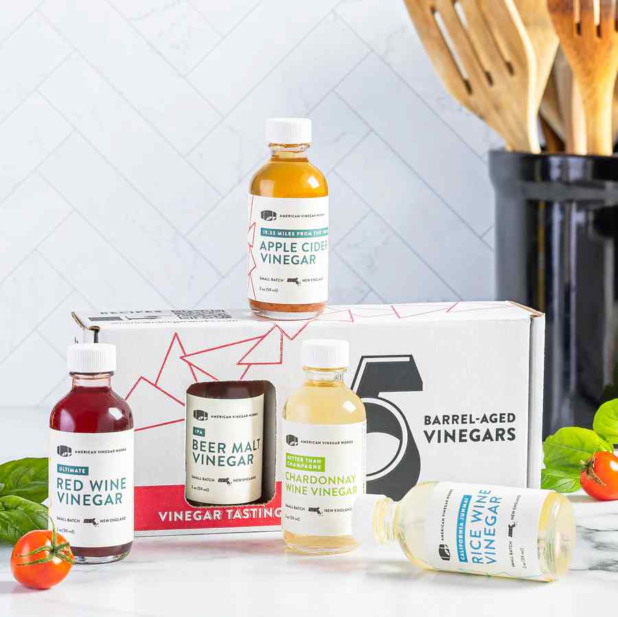 American Vinegar Works Essentials Plus Vinegar Sampler pack featuring five barrel-aged vinegar bottles on display.