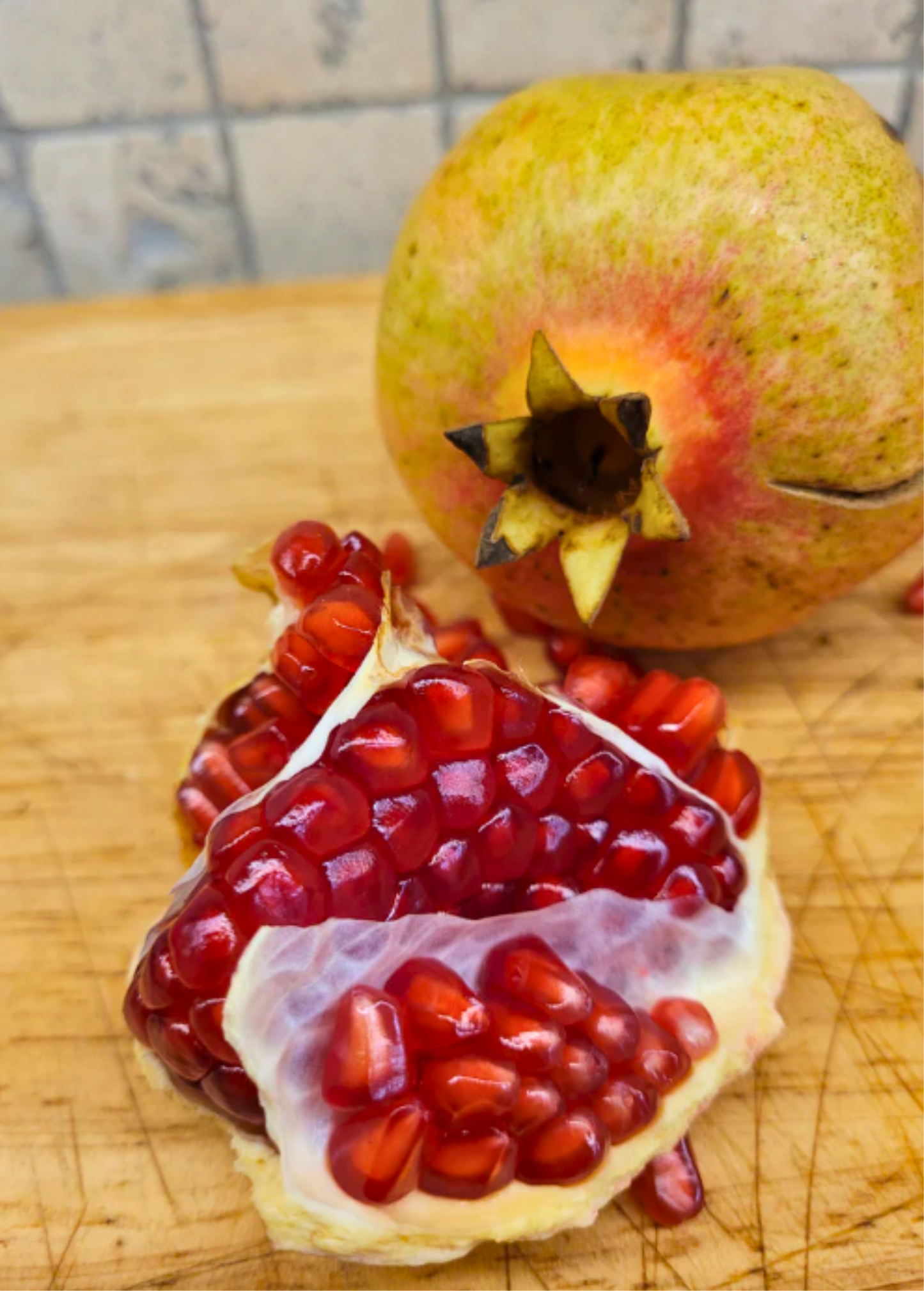 Healthy Azadi pomegranate tree by Sow Exotic, tropical fruit tree with lush green foliage and developing fruit on branches.