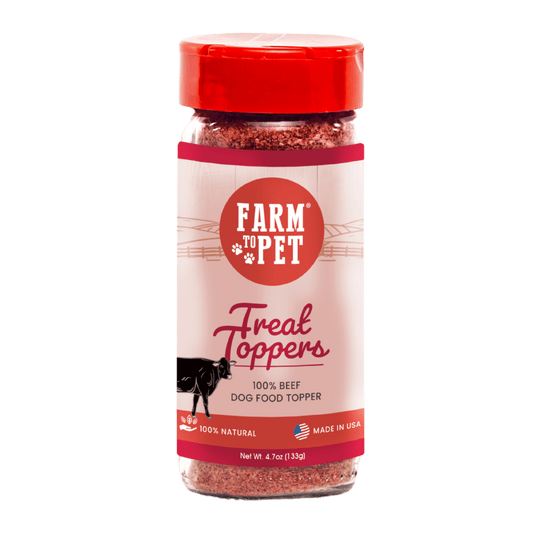 A clear jar with a red lid holds Farm To Pet Treat Topper Beef Dog Food Topper. The pink and red label shows a cow, notes its 100% beef, single ingredient, made in the USA, and all-natural.