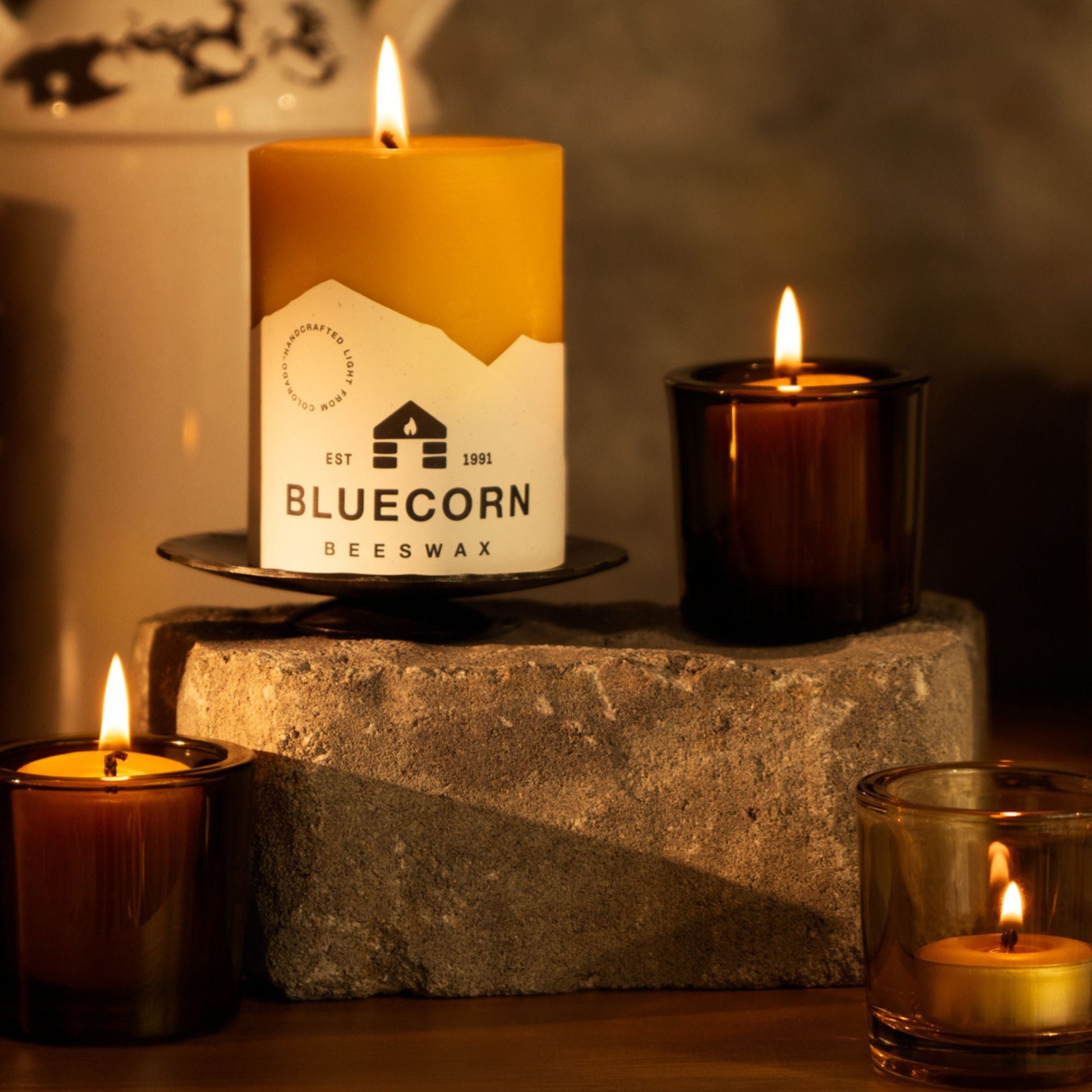 Bluecorn Candles pure beeswax pillar candles with glass holders, featuring fall-themed decorative votives and tea lights.
