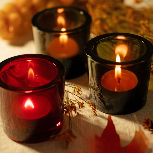 Set of three Bluecorn Candles pure beeswax tea light candles in heavy glass votive holders, showcasing warm light and natural beeswax texture.