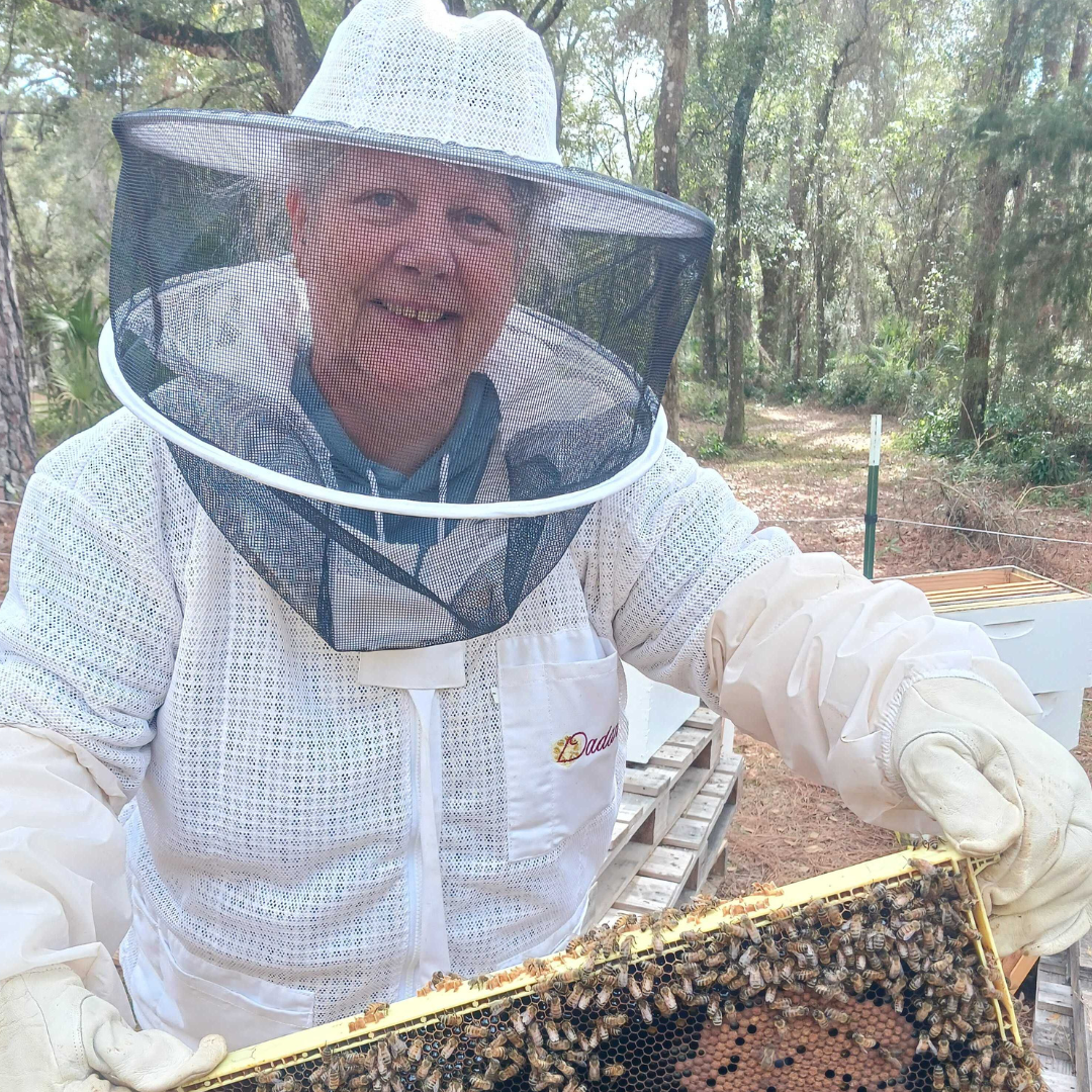 Raw, unfiltered wildflower honey from the Ocala National Forest, shown in a jar with golden honey and honeycomb pieces.