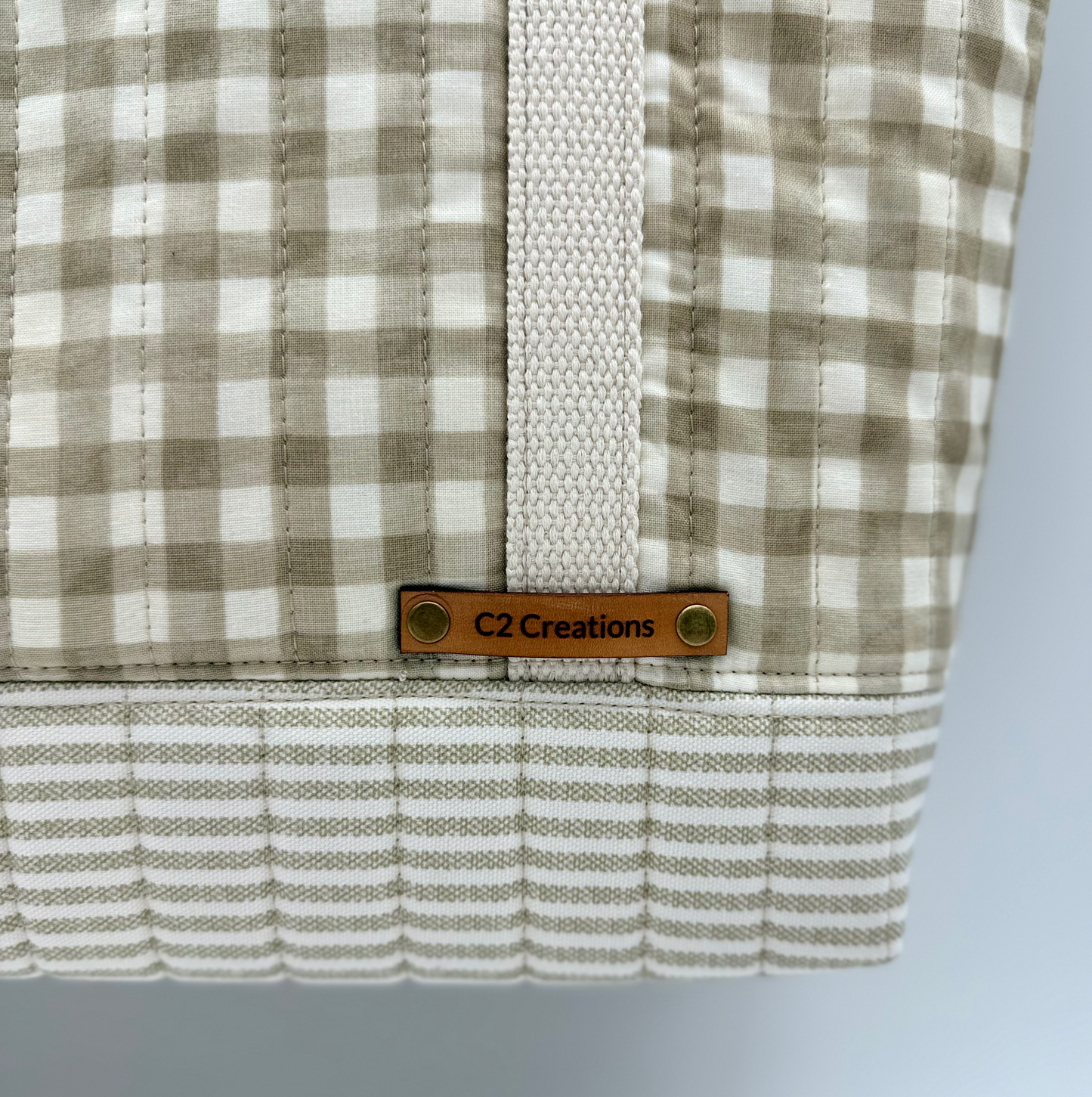 Handmade Gingham tote bag by C2 Creations LLC with taupe and cream pattern and quilted bottom, leather patch detail visible.
