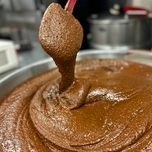 Creamy cacao cashew spread from Mixed Up Foods in an 8 oz jar, showing a spoonful of rich nut butter with chocolate and nut textures.