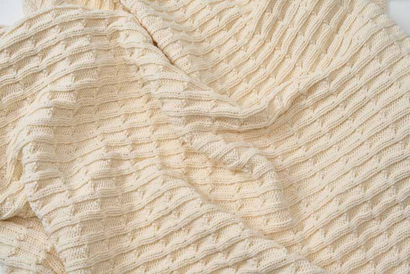 Closeup of a soft, 100% cotton knitted baby blanket by American Blossom Linens, showcasing cozy and gentle texture for infants.