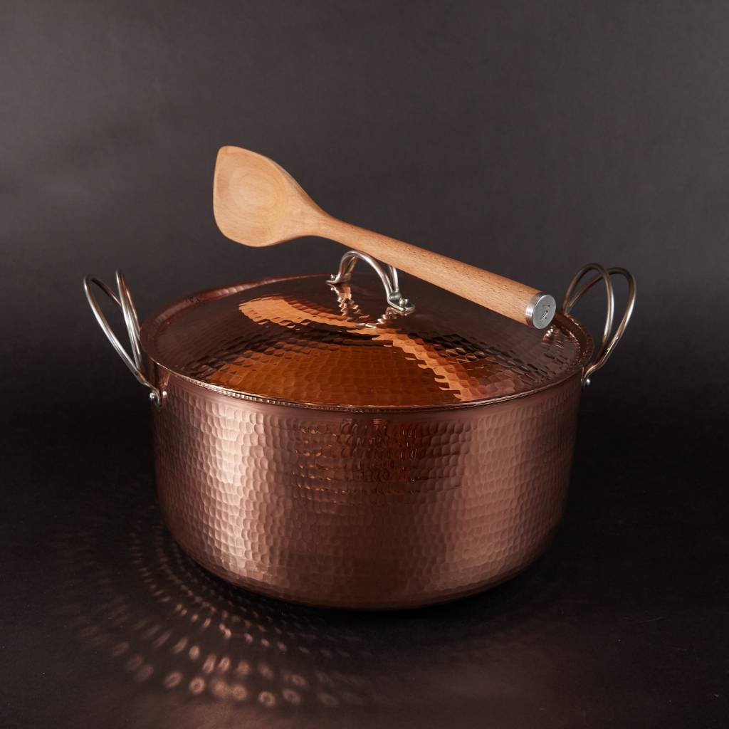 Copper Dutch oven by Sertodo with a matching ladle resting on the lid, showcasing a large, beautiful cookware set.