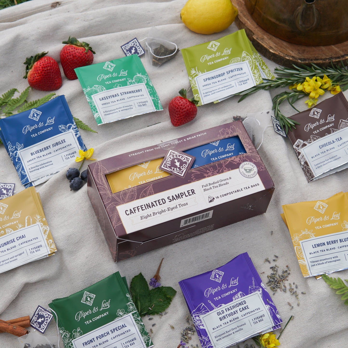 Box of 12 Piper and Leaf Tea Co. caffeinated tea bags in a tasting flight display, featuring various tea bag packaging and branding.