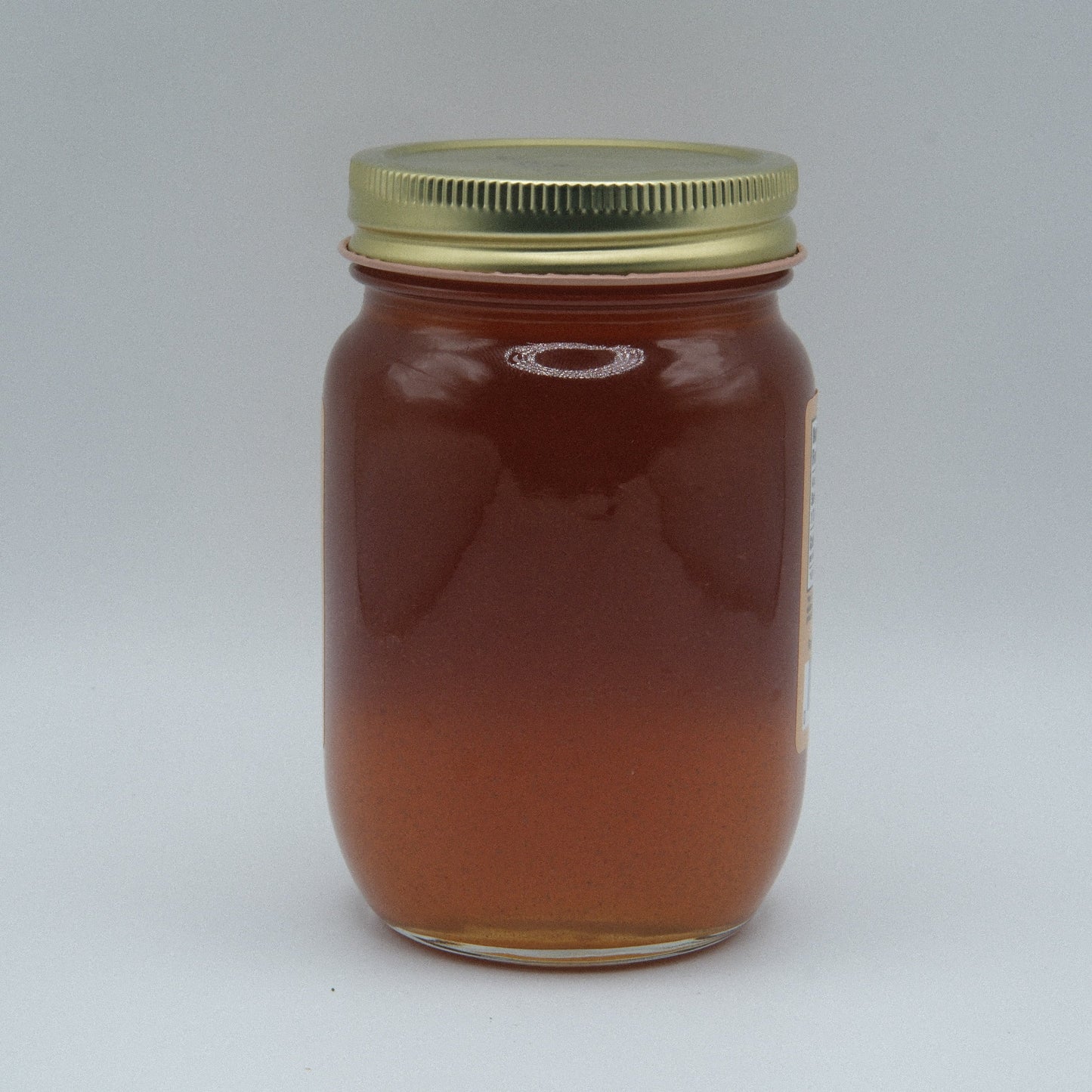 Canned apple cinnamon jelly by Amish Country Store in a jar, showing the amber-colored jelly with a label.