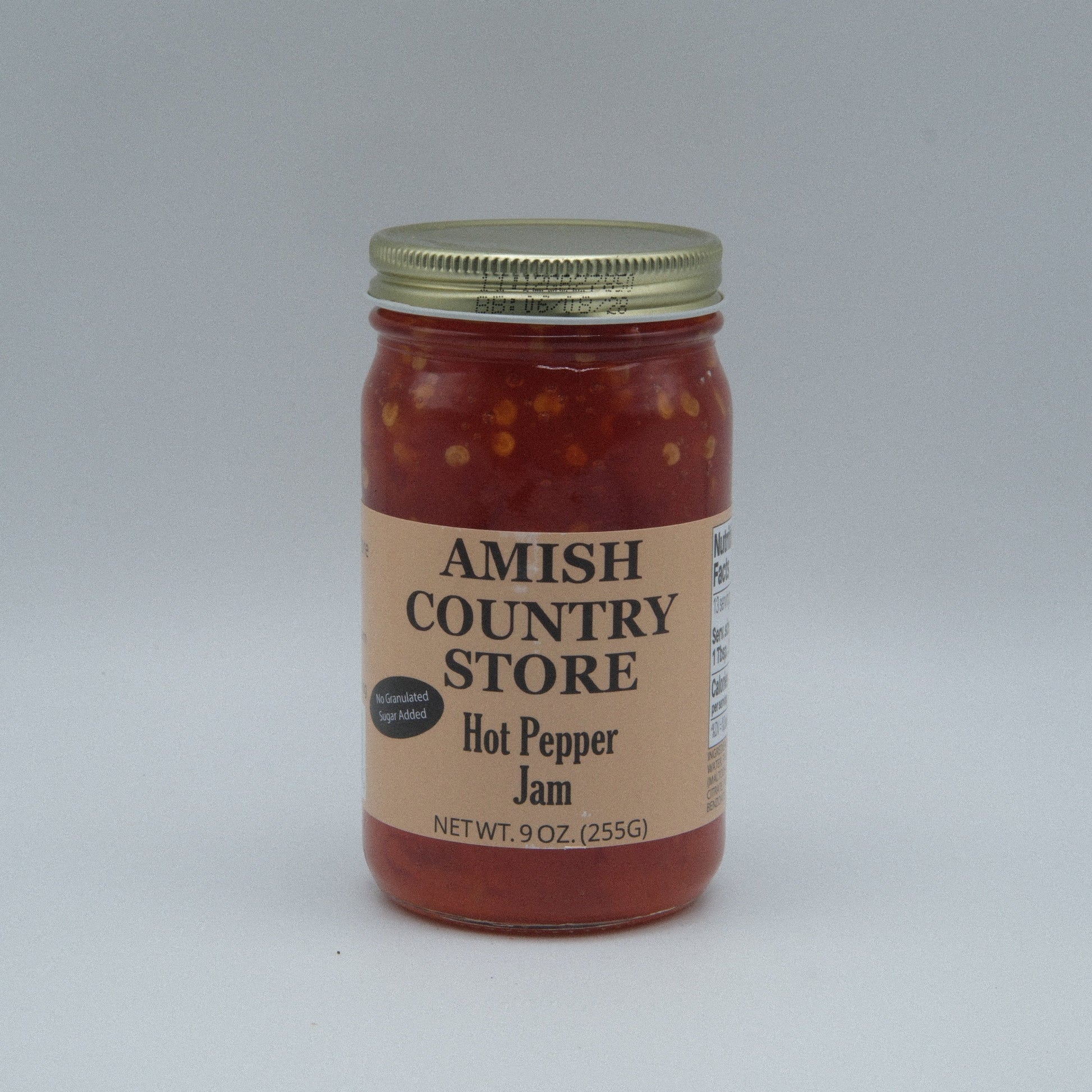 Canned Amish Country Store Hot Pepper Jam with no sugar added in a 9 oz jar, showing vibrant red peppers and jam inside.