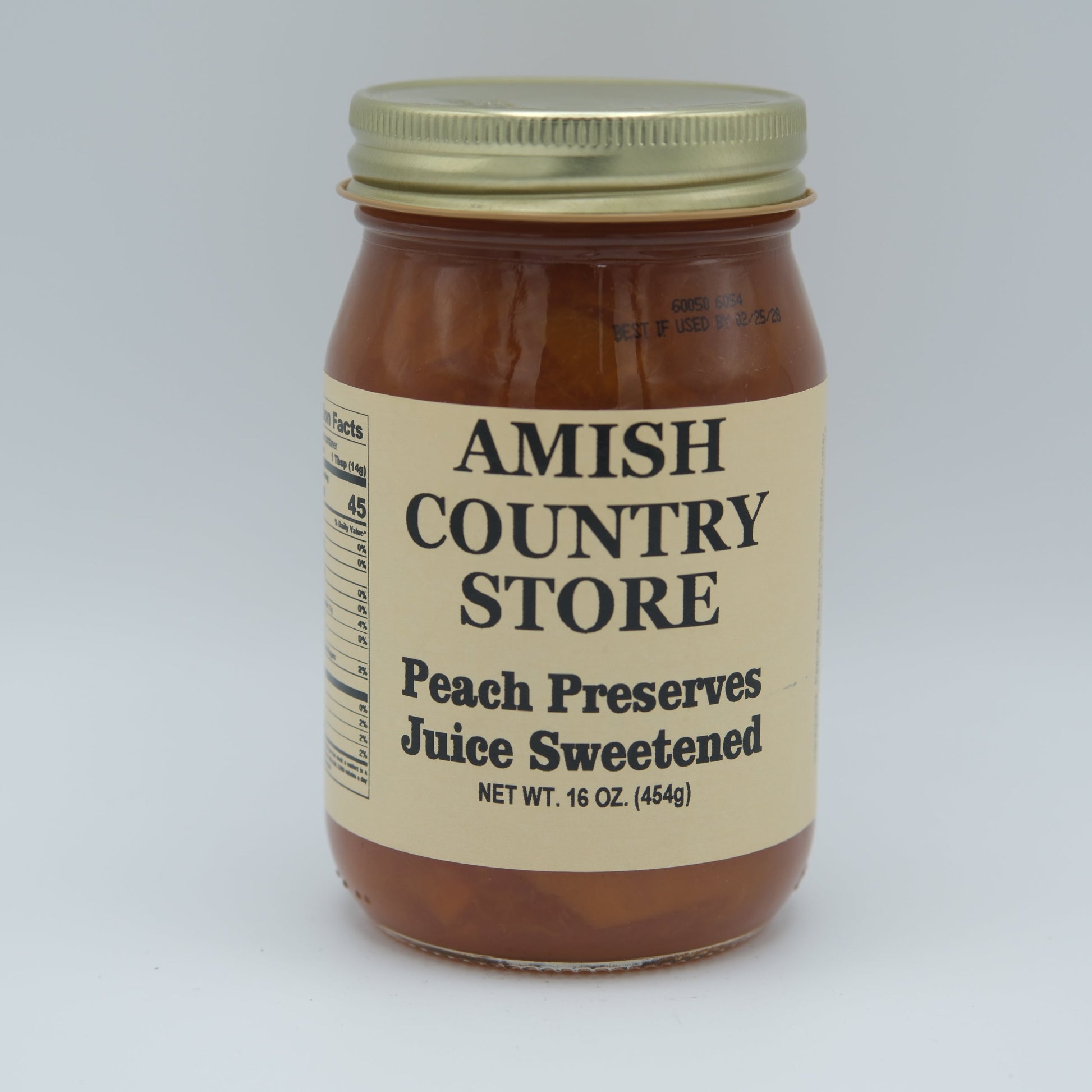 Canned peach preserve juice in a 16 oz jar with Amish Country Store label, showcasing the preserved peach liquid inside.