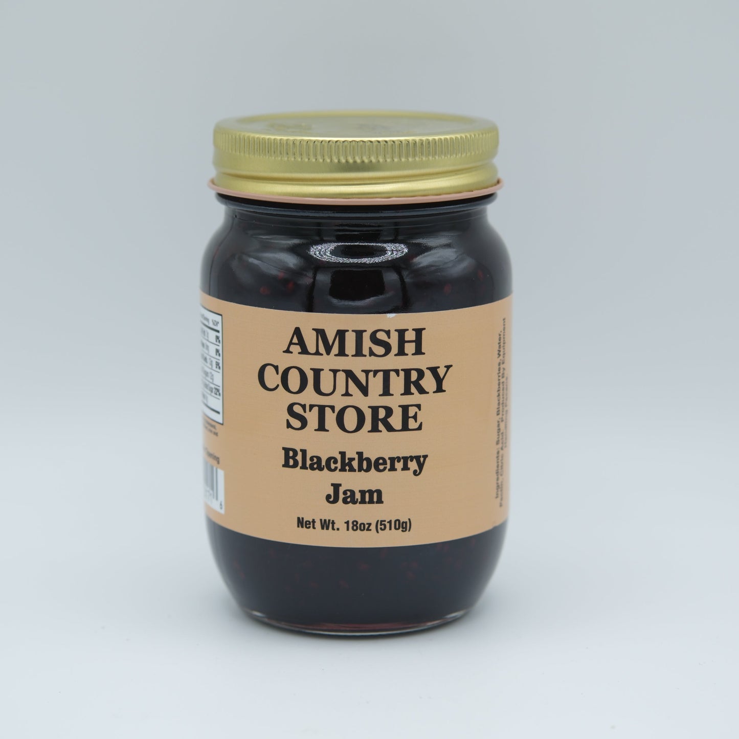 Canned Amish Country Store blackberry jam jar, 18 oz with a label, glossy lid, and fresh blackberry fruit visible inside.