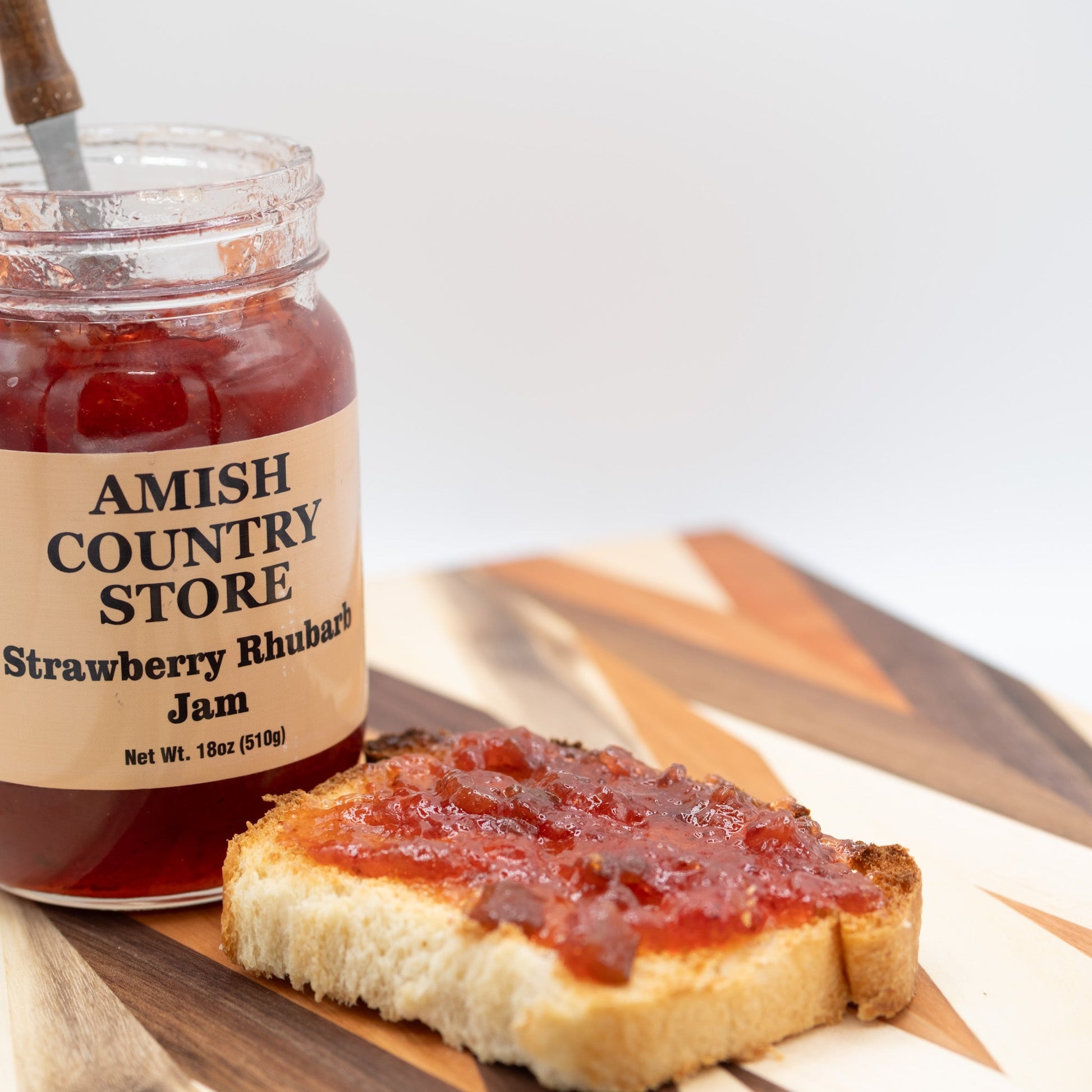 Canned Amish Country Store Strawberry Rhubarb Jam jar with label and red jam visible inside, 18 oz size.
