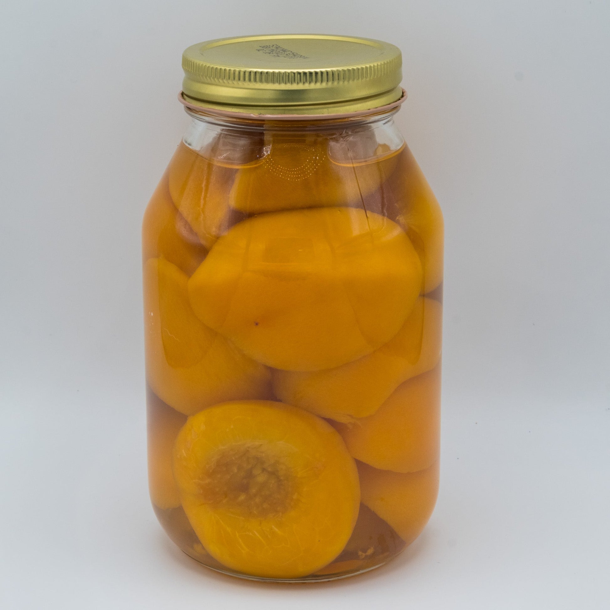 Canned Spiced Peaches in a 32oz jar by Amish Country Store, showing glossy peaches with spice accents in jar.