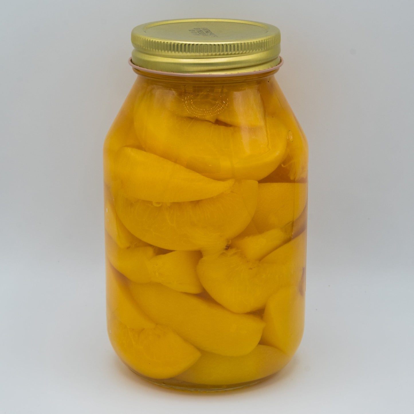 Canned peach slices in a 32oz jar from Amish Country Store, showing golden peach slices in syrup on a white background.