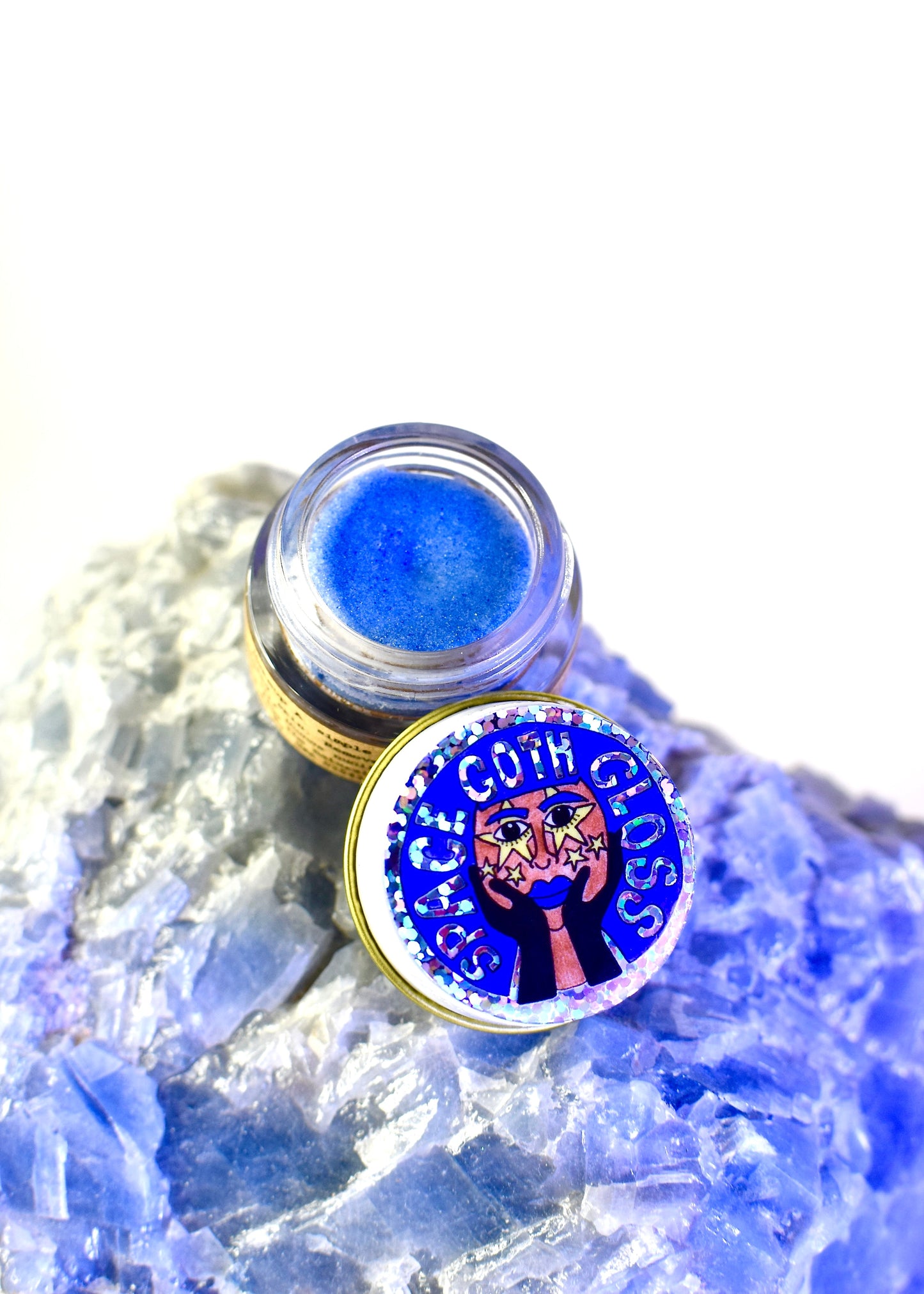 Close-up of space goth gloss by plant makeup showing its shiny, dark purple liquid formula in a clear applicator tube.