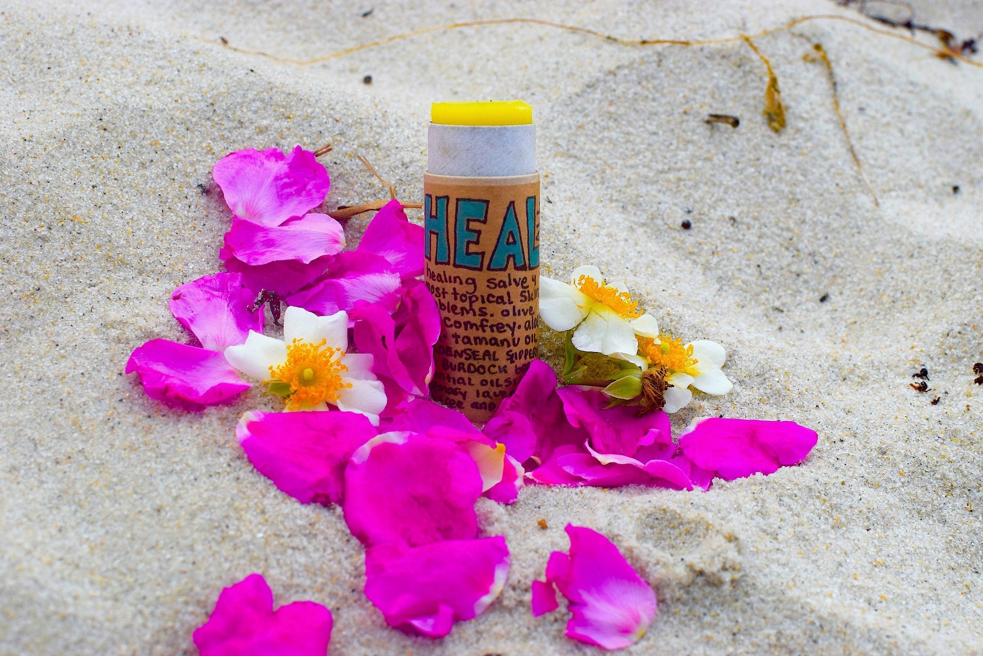 Close-up of plant makeup Heal All Balm jar showing the label and natural ingredients on a wooden surface.