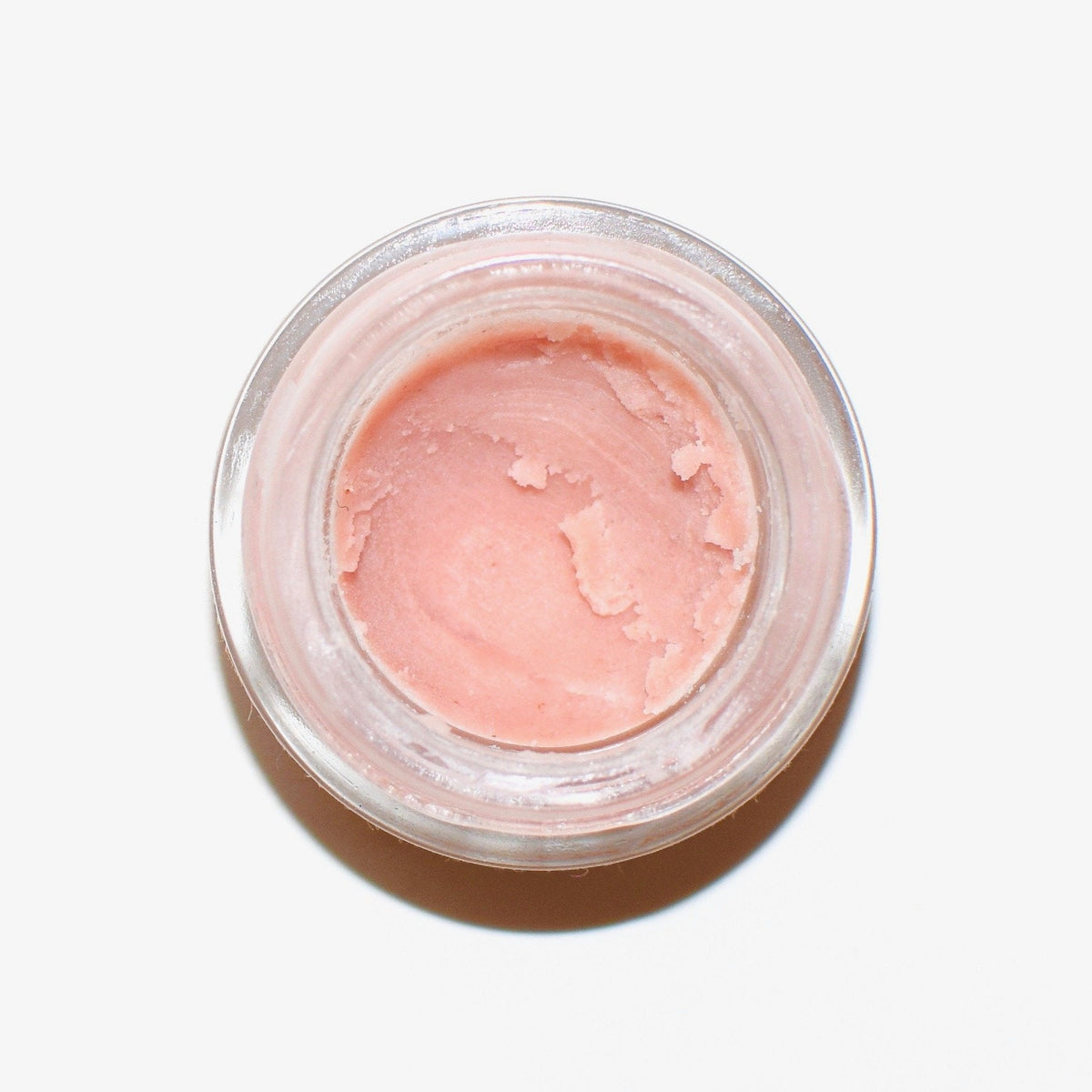 Plant Makeup Strawberry Dreamsicle Lip Balm Scrub in a clear jar with a pink and white creamy texture and fresh strawberry pieces.