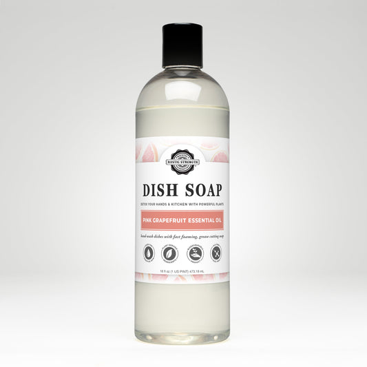 A clear bottle of Rustic Strength Dish Soap | Pink Grapefruit, biodegradable and scented with pink grapefruit essential oil, features a white label with grapefruit illustrations and black text, set against a plain white background.
