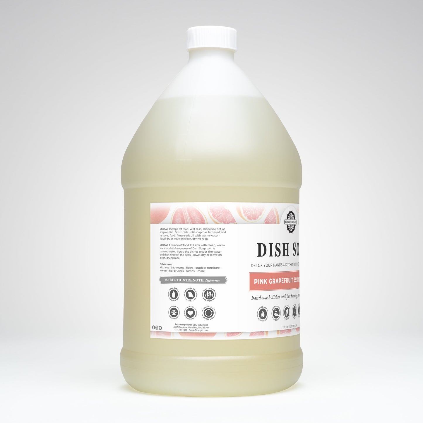 A large, translucent plastic gallon jug with a white cap contains Rustic Strength Dish Soap | Pink Grapefruit. The label has black text, pink grapefruit illustrations, and product info. Inside is pale yellow soap with a fresh grapefruit scent.