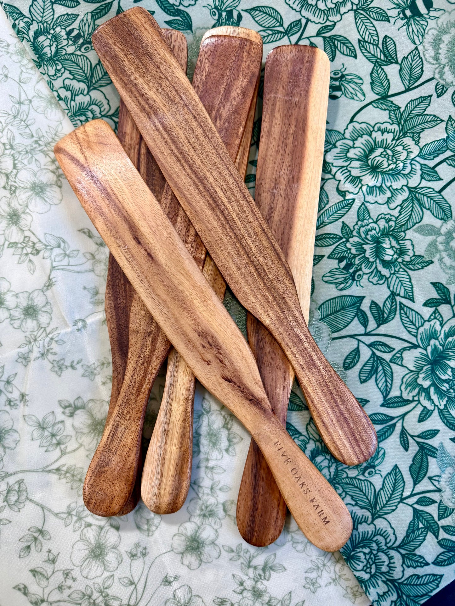 Handcrafted wooden Spurtle from Five Oaks Farm, showcasing its smooth finish and traditional design on a rustic background.
