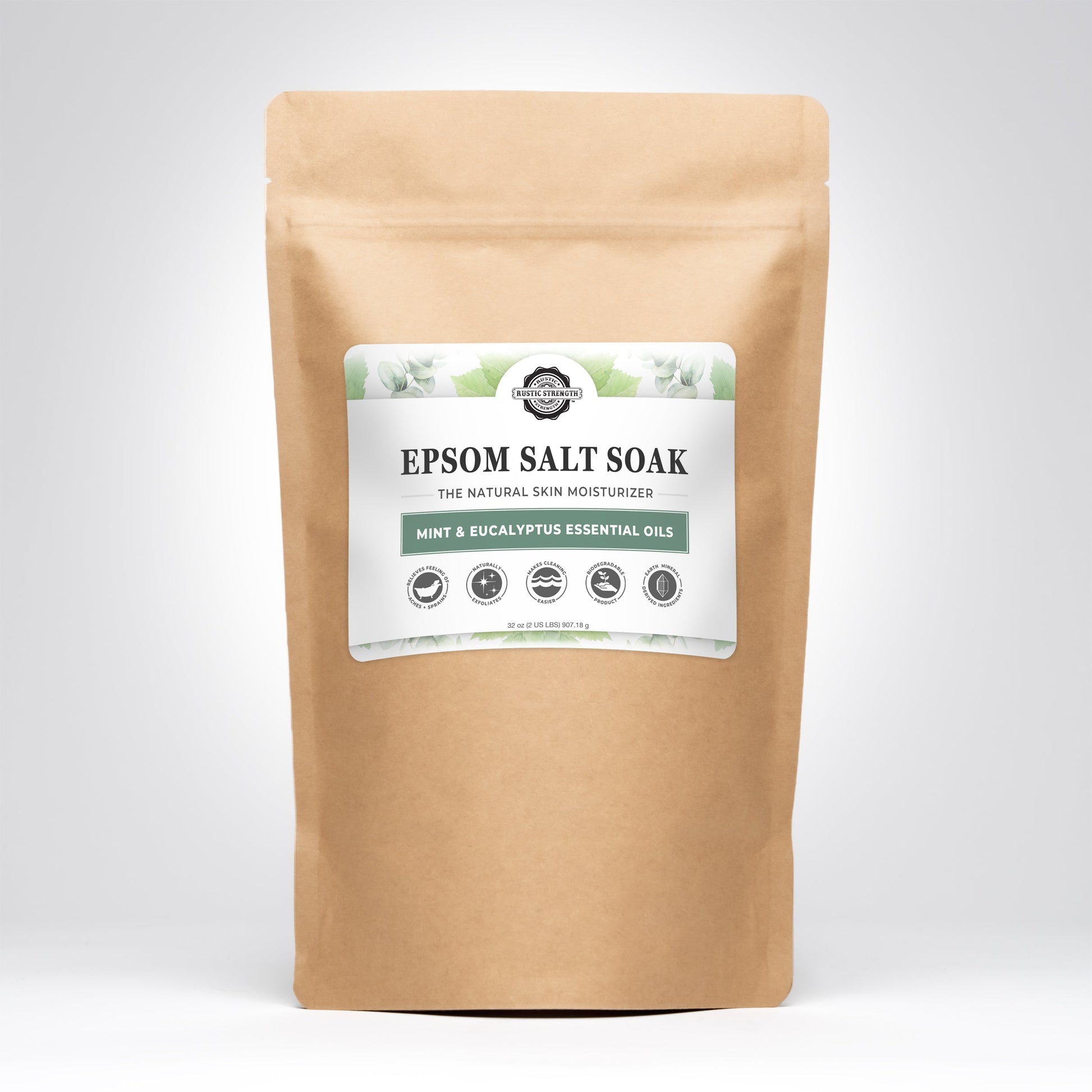 A brown resealable pouch labeled Rustic Strength Epsom Salt Soak | Mint & Eucalyptus stands upright on a white background. The label features green leaf accents, product info, and notes its grey-water safe formula.