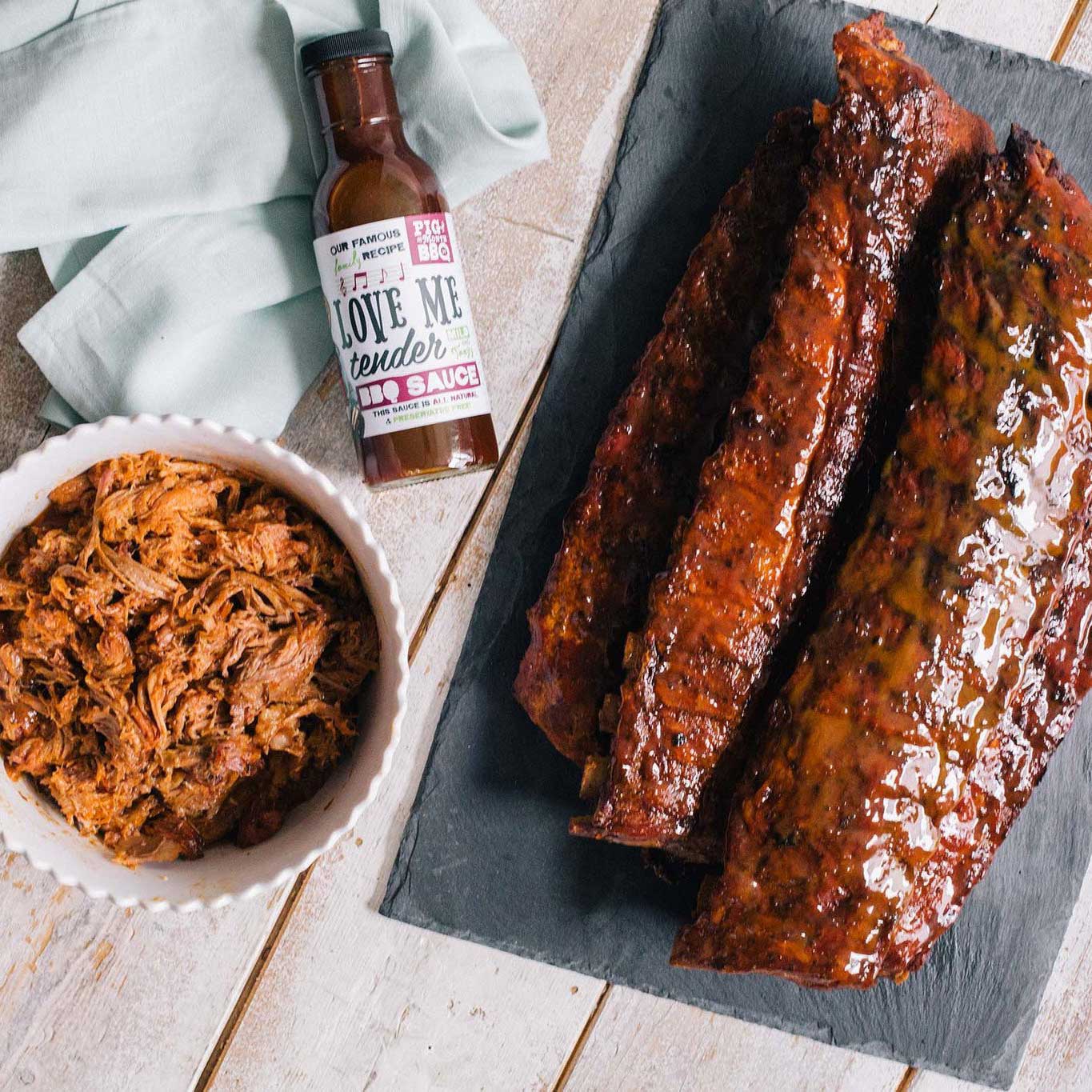 Family dinner with assorted BBQ meats for six from Pig of the Month BBQ, including ribs, brisket, and sausage on a serving platter.