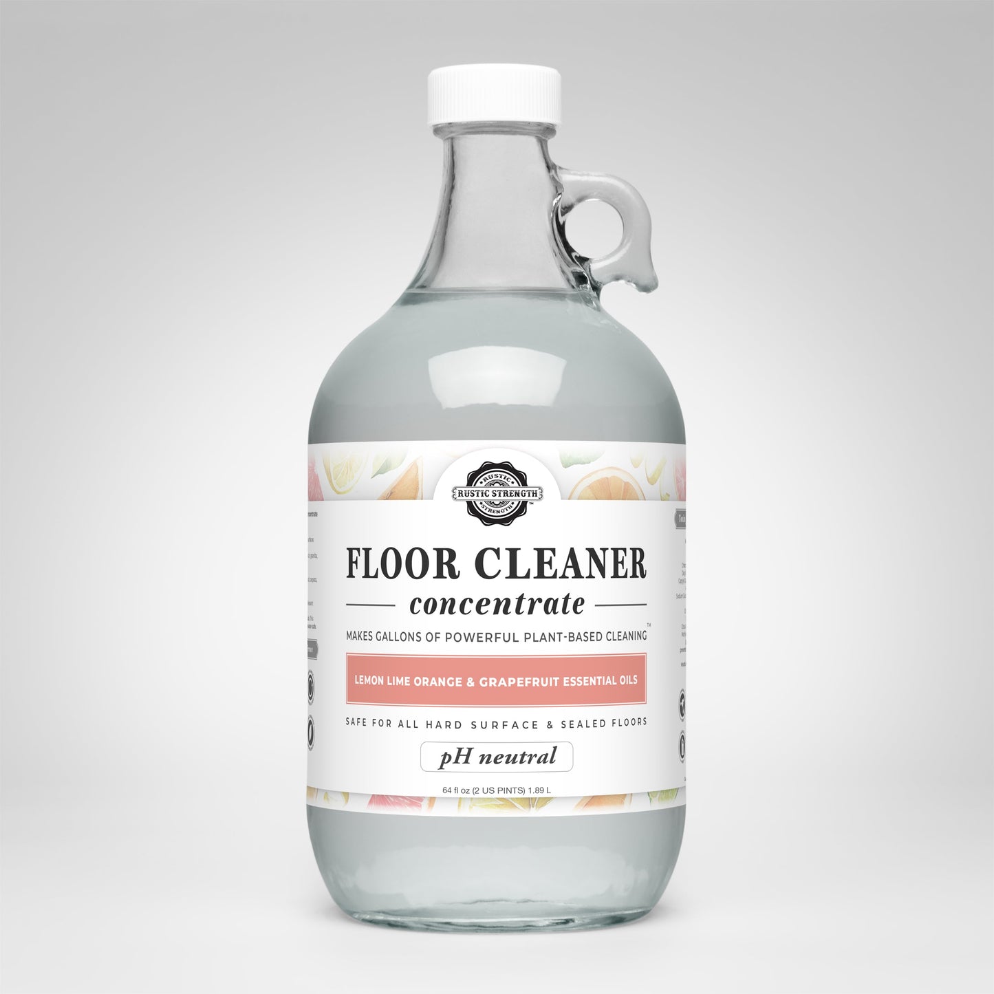 A clear glass bottle with a handle holds Rustic Strength Floor Cleaner Concentrate | Lemon, Lime, Orange & Grapefruit. The white label notes essential oils, pH neutral formula, and safe for hard surfaces.