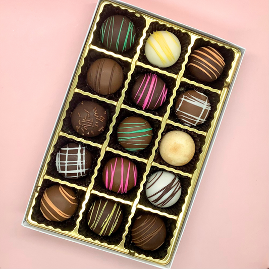 Assorted fudge truffles in a medium Fudge Co. box, featuring various smooth, creamy chocolates with decorative toppings.