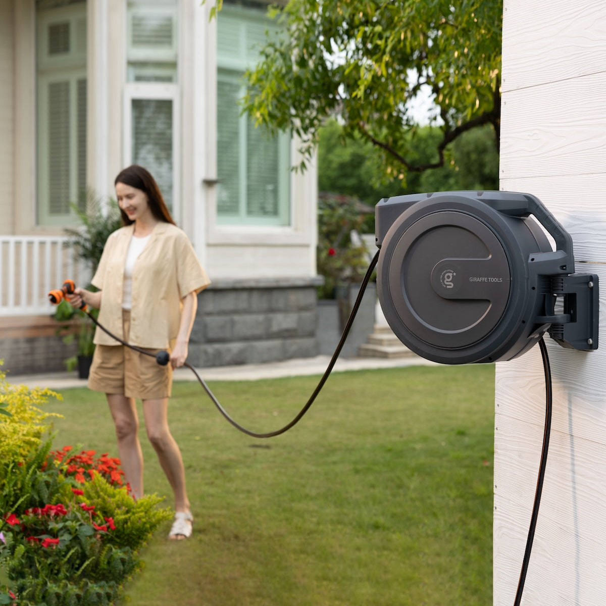 Giraffe Tools US retractable garden hose reel with 62ft to 155ft capacity, mounted on a garden wall with hose neatly wound.
