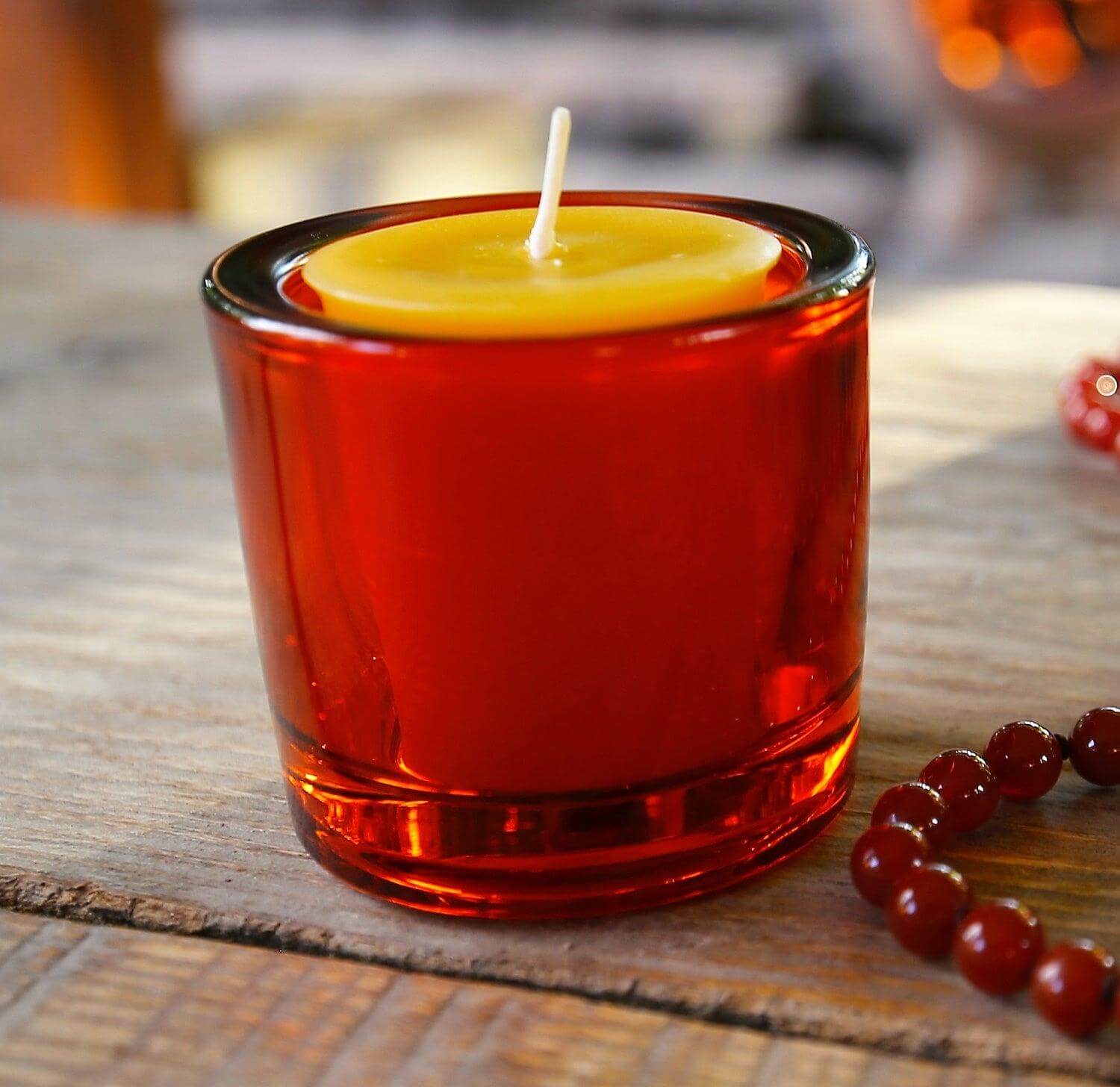 Bluecorn Candles heavy glass votive candle holders made from 50% recycled glass, featuring a clear, sturdy design with a lit candle inside.