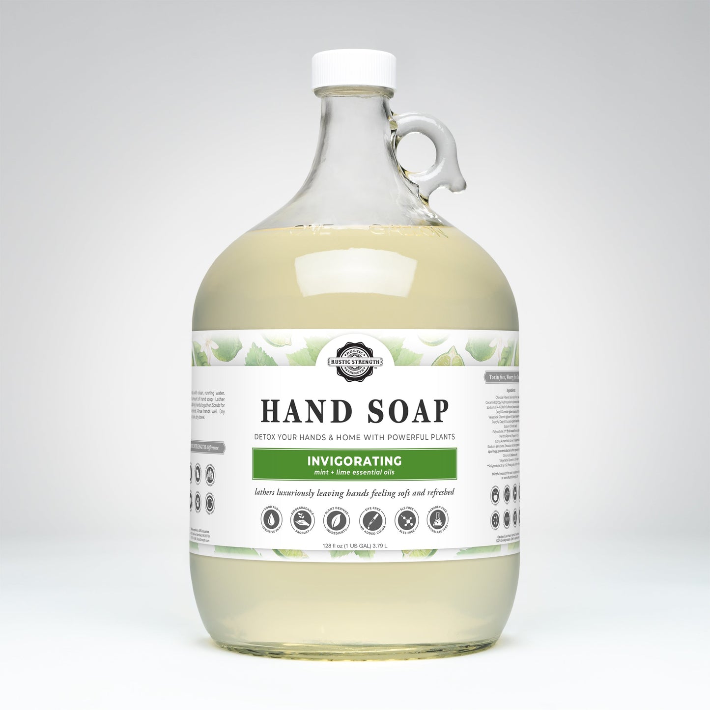 A large, clear jug of Rustic Strength Hand Soap | Invigorating features a handle, green leaf designs, icons, visible light yellow soap inside, and a label reading Hand Soap | Invigorating with lime & green tea. Biodegradable formula.
