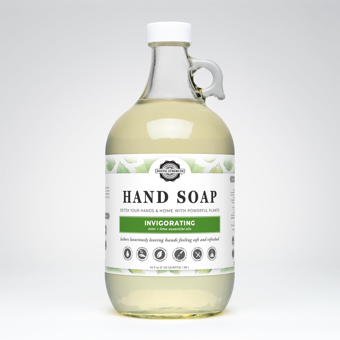 Rustic Strength Hand Soap | Invigorating comes in a clear glass bottle with a handle and white label, featuring peppermint lime essential oil. The biodegradable, pale yellow liquid delivers a refreshing, eco-friendly clean.