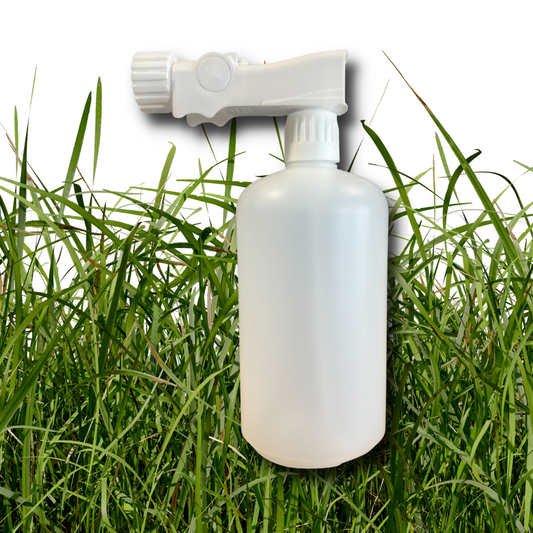 The Elm Dirt Hose End Sprayer and Empty Bottle, a white plastic garden sprayer with adjustable nozzle, is shown in front of tall green grass on a white background.
