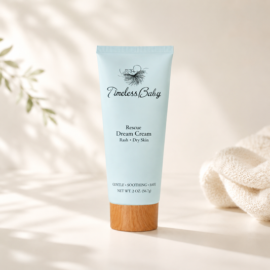 Tube of Timeless Baby Rescue Dream Cream for rash and dry skin, with a wooden cap, placed on a light surface with a beige towel nearby.