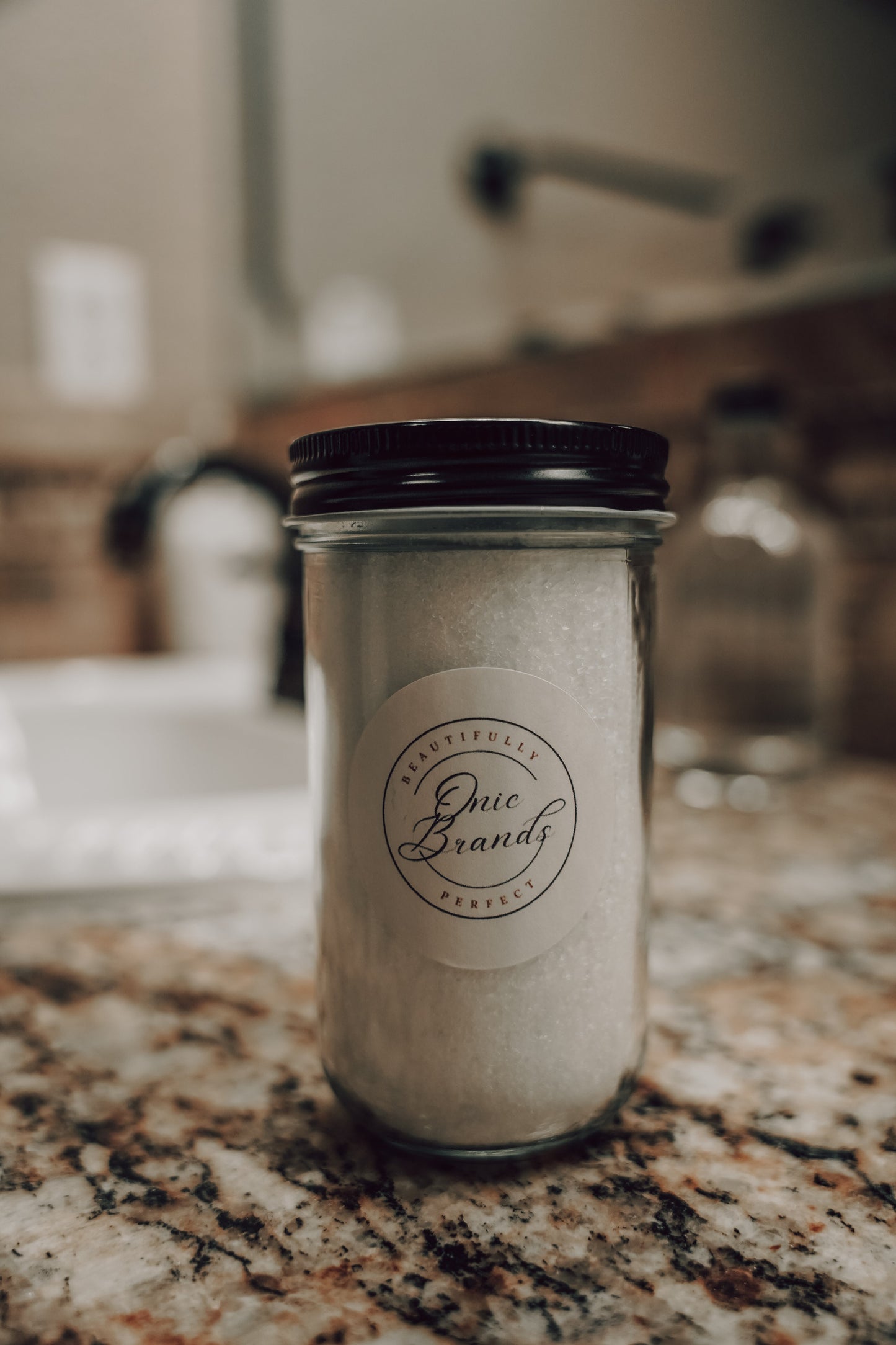 Magnesium bath and foot soak by Onic Brands LLC in a clear jar with a scoop, showcasing the bath additive's texture and packaging.