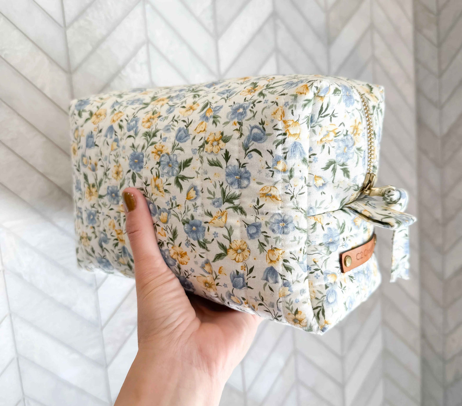 Handmade floral makeup bag by C2 Creations LLC with blue and yellow garden pattern, featuring a zip closure and compact design.